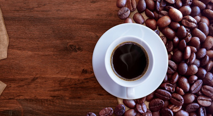 Coffee cup and coffee beans on wood table background vintage style for graphic design