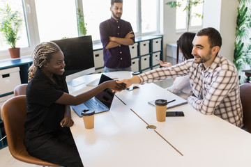 Welcome to our team. Young modern men in smart casual wear shaking hands while working in the creative office