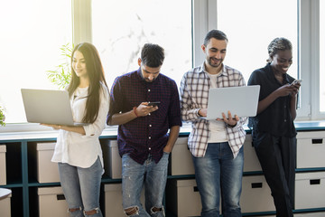 Mixed race Business people using digital devices standing in modern office