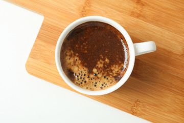 Cutting board with cup of fresh coffee on white background, space for text and top view