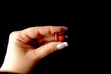 woman hand holding an orange transparent pill