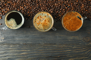 Flat lay composition with cups of coffee and coffee beans on wooden table, space for text and top view