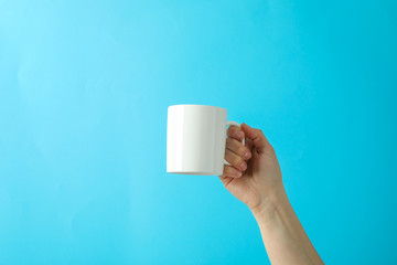 Female hand holding white cup against color background, space for text