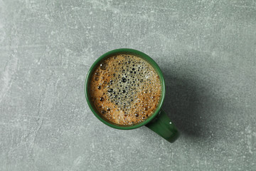 Cup of coffee with frothy foam on grey background, top view and space for text. Coffee time accessories