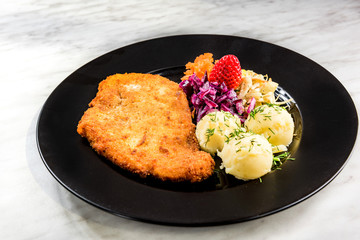 Pork meat served with potato and salad on plate