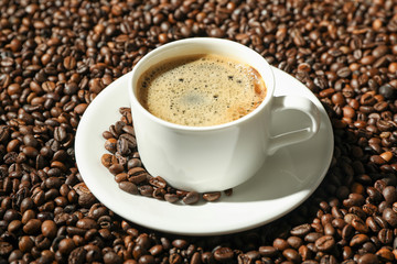 Cup of coffee with frothy foam on beans background, space for text. Coffee time accessories