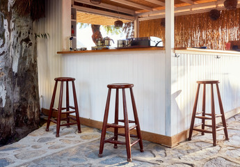 Three brown wooden stools and an outdoor pub counter