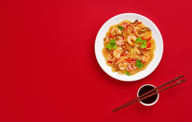 Glass noodle with shrimps and vegetables on the red background