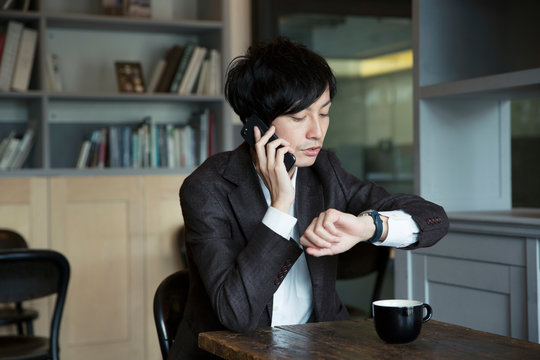 電話をしながら時計を確認する20代男性