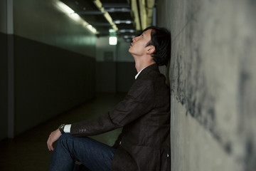 暗い廊下にしゃがみ考え込む男性