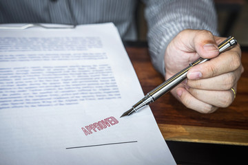 Close up hands of businessman pointing to signing and stamp on paper document to approve business investment contract agreement