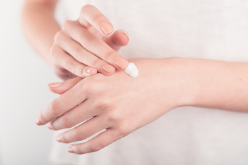 Fototapeta na wymiar Spa treatment. Close Up of female hands applying hand cream. Woman holding cream tube and applying moisturizer cream on her beautiful hands for clean and soft skin.