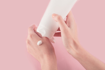 Spa treatment. Close Up of female hands applying hand cream. Woman holding cream tube and applying moisturizer cream on her beautiful hands for clean and soft skin.