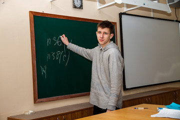  Pupil teen boy standing at the blackboard in the classroom