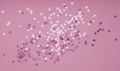 Festive background with silver star confetti on purple background. Flat lay for holiday, Christmas or party design.