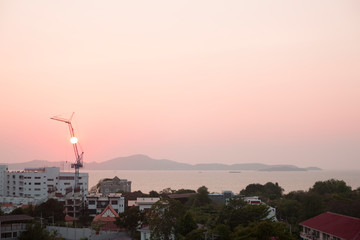 Building on the sea cost. Construction equipment at pink sunset. Real estate on the beach.