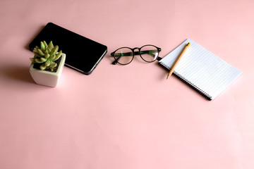 Notebook, pen, glasses, computer, arranged on a pink background, imagine working in the organization
