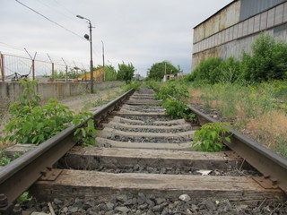 old abandoned railroad with rusty rails and rotting sleepers