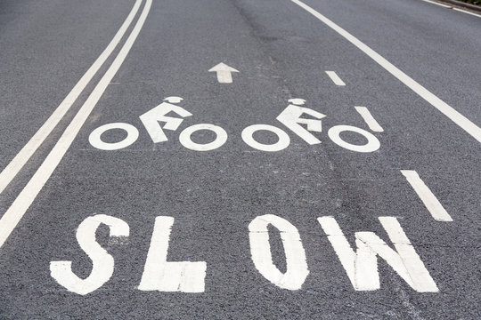 Bike lane road markings and Slow sign on a pavement