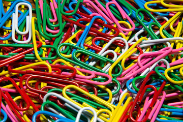 closeup of colorful paper clips on wooden desk background 