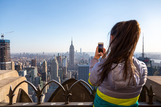 Tourist taking picture of New York City cityscape. Young woman looking at Manhattan panorama