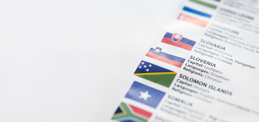 List of countries with national flag, languages and religions of these countries. Paper background with focus on Slovenia with capital city Ljubljana. White copy space.