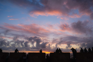 Nature landscape silhouette view, group of people watching sunset at Essaouira ramparts, Morocco....