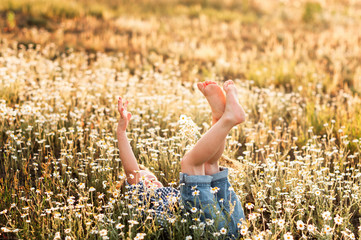 funny little boy lying in a chamomile field.