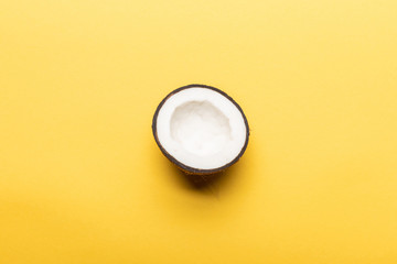 top view of ripe coconut half on yellow background with copy space