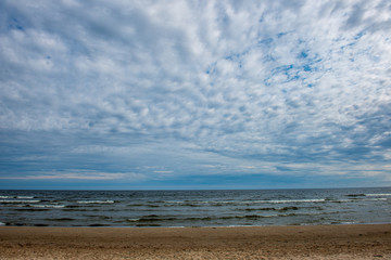 empty sea beach in summer with waves and broken clouds