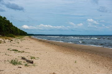 empty sea beach in summer with waves and broken clouds