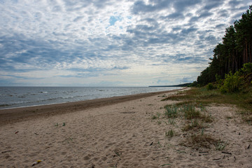 Fototapeta na wymiar empty sea beach in summer with waves and broken clouds