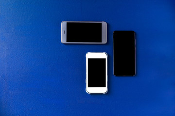 three blank cell phones on a blue background
