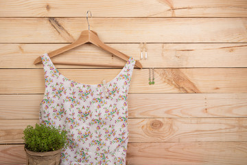 Fototapeta na wymiar Fashion trends - dress in floral print on hangs on hanger and earrings on wooden background