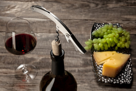 Delicisious and tasty food and drink. A bottle and a glass of red wine with fruits over weathered wooden background. Top view with copy space to insert your text or image for ad. Grape and cheeseplate