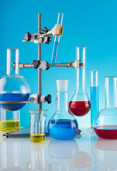 Biological laboratory. A tripod with variety of chemical glass and colored liquids on a blue background