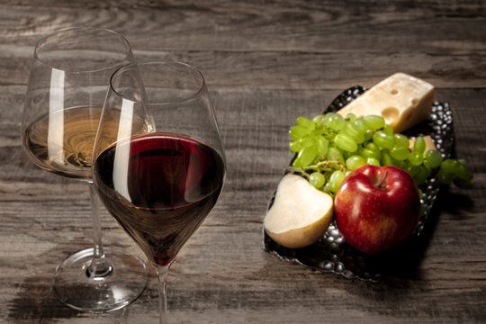 Delicisious and tasty food and drink. A bottle and glasses of red and white wine with fruits over wooden background. Top view with copy space to insert your text or image for ad. Grape and cheeseplate