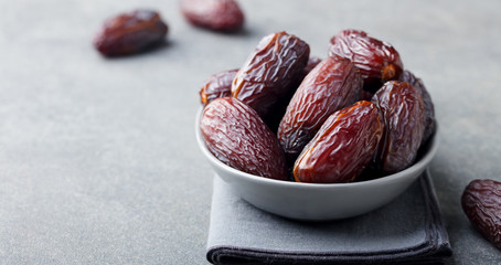 Fresh medjool dates in bowl. Grey background. Copy space.