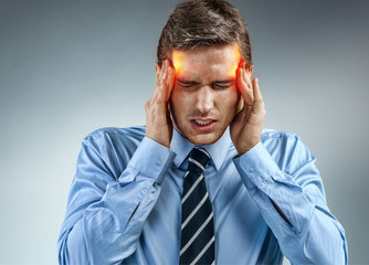 Young businessman with pain in his temples. Photo of man suffering from stress or a headache...