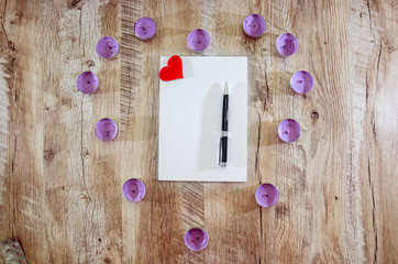 notebook with pen and red heart on wooden background. View from above.