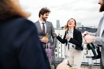 A group of joyful businesspeople having a party outdoors on roof terrace in city.