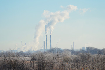 Modern landscape with factory pipes at a distance from which smoke is polluting the air