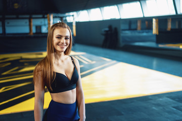 Young attractive blonde girl with smile portrait on crossfit gym background