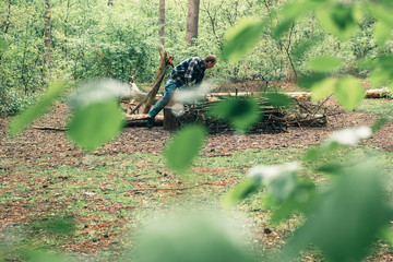 Young man preparing campfire in forest.