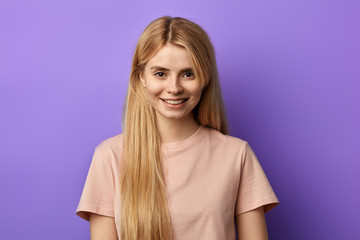 Fototapeta premium positive fair-haired woman in beige T-shirt looking at the camera. close up photo. isolated blue background