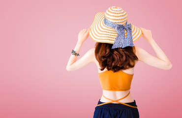 Beautiful woman wearing a straw hat and sexy suit on pink background with Summer concept.