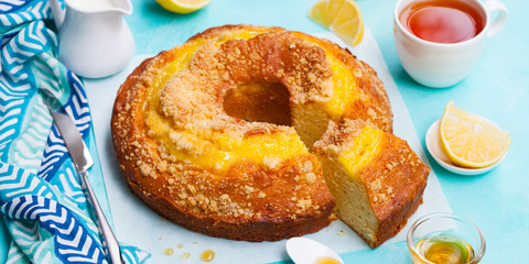 Lemon bundt cake with cup of tea. Blue background. Close up.