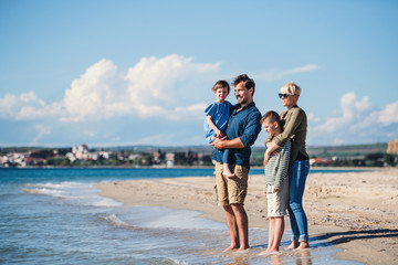 Young family with two small children standing outdoors on beach.