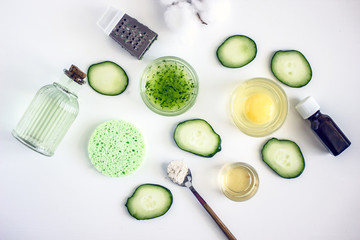 Top view of ingredients for preparing homemade cosmetics - face mask of fresh cucumber, a number of slices of fresh cucumbers, honey, egg yolk, oatmeal, napkins. Natural skin care
