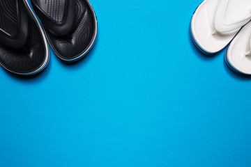 Flip flops on a blue isolated background. Black male and female white.
